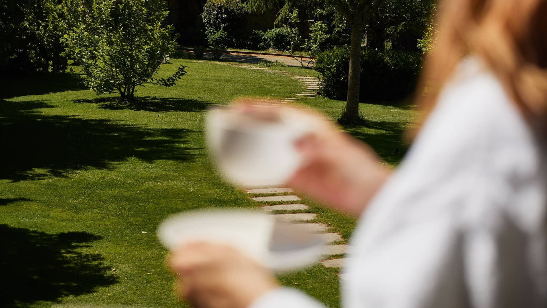Mujer agarrando una taza de cafe en el jardín del hotel